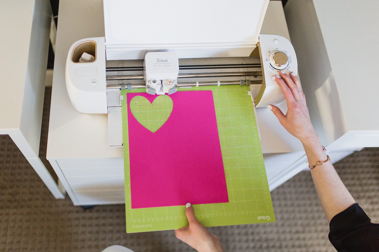 Machine de découpe avec une feuille de papier rose posée sur son tapis