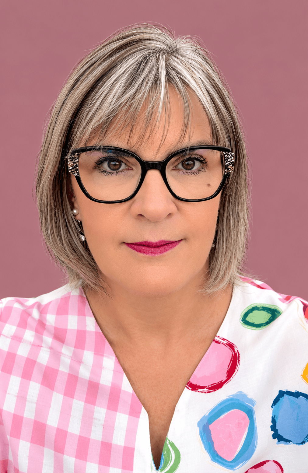 Portrait de Valérie Morin, créatrice de Créa-Val, souriante, avec des lunettes noires et une blouse à motifs colorés.